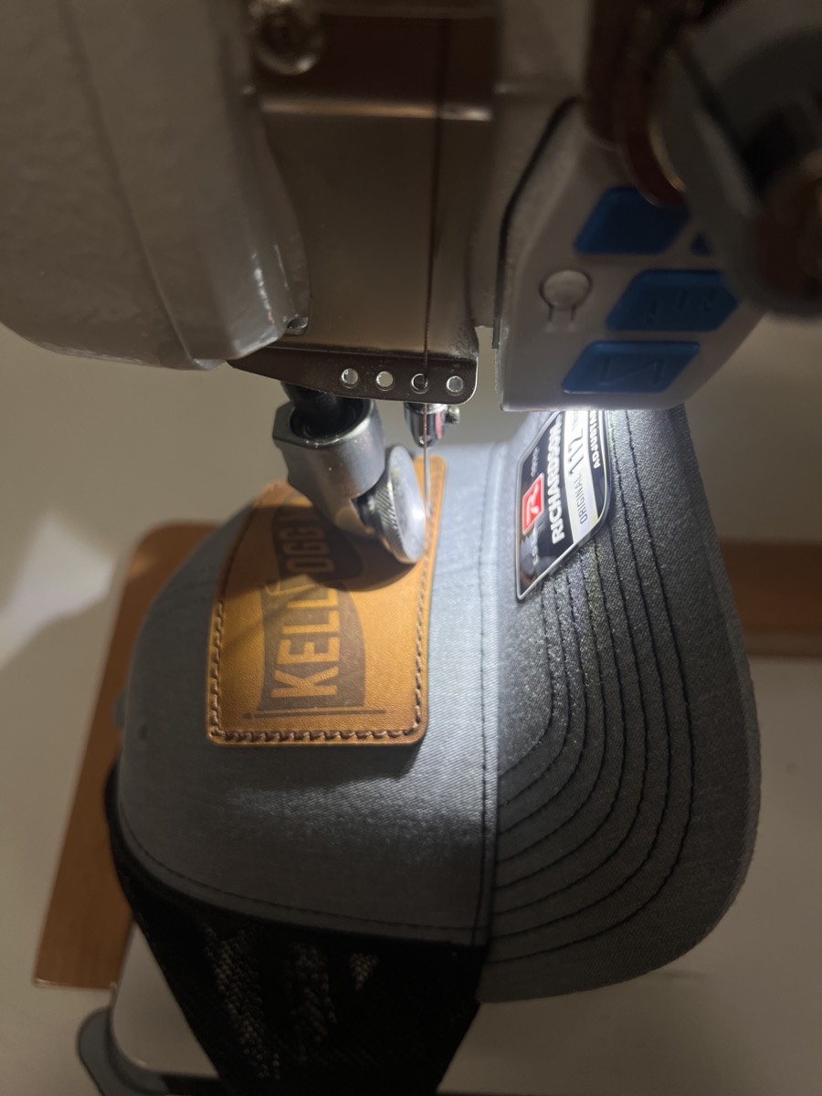 Embroidery machine stitching a leather patch onto a cap